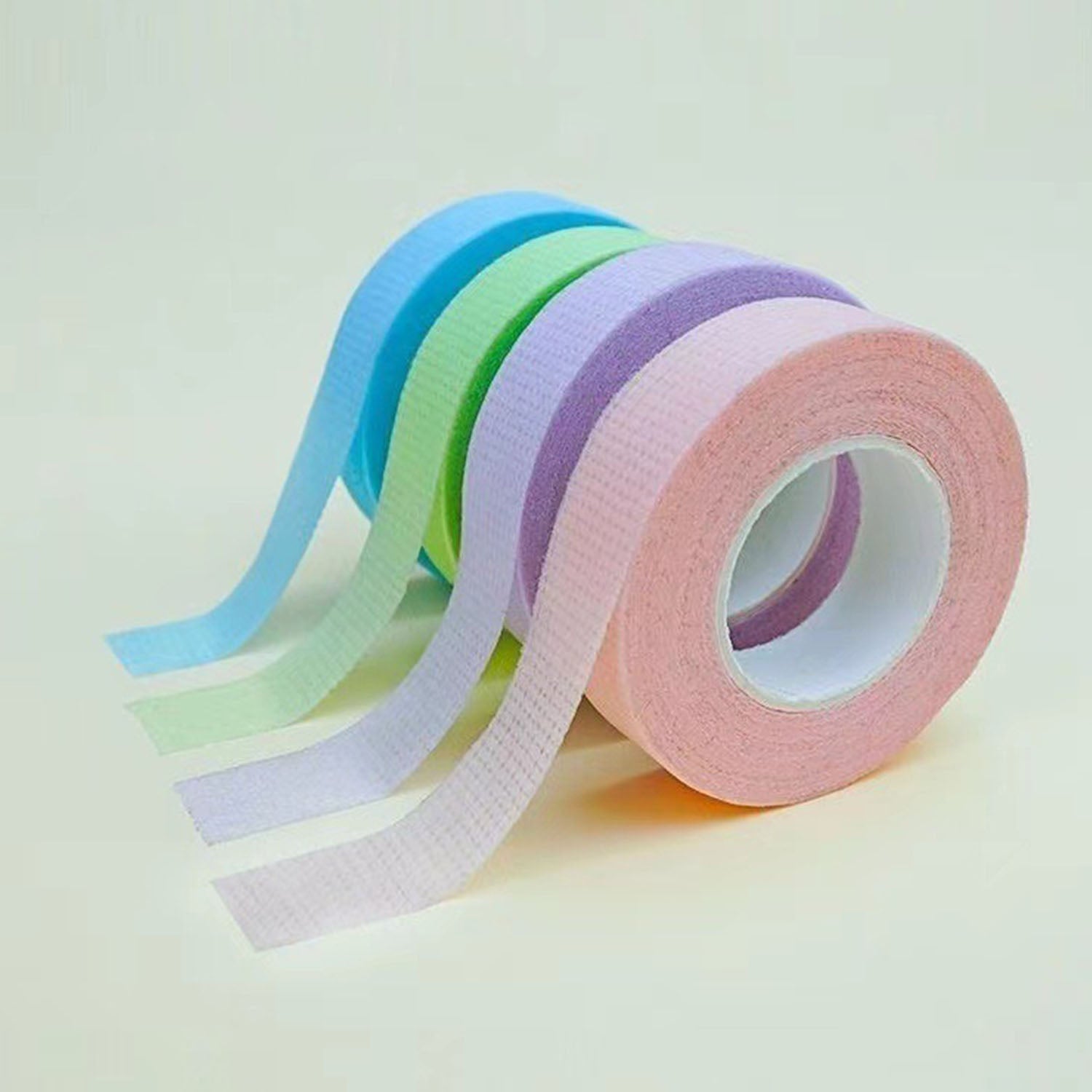 Four YSEN’S micropore lash tape rolls in blue, green, purple and pink